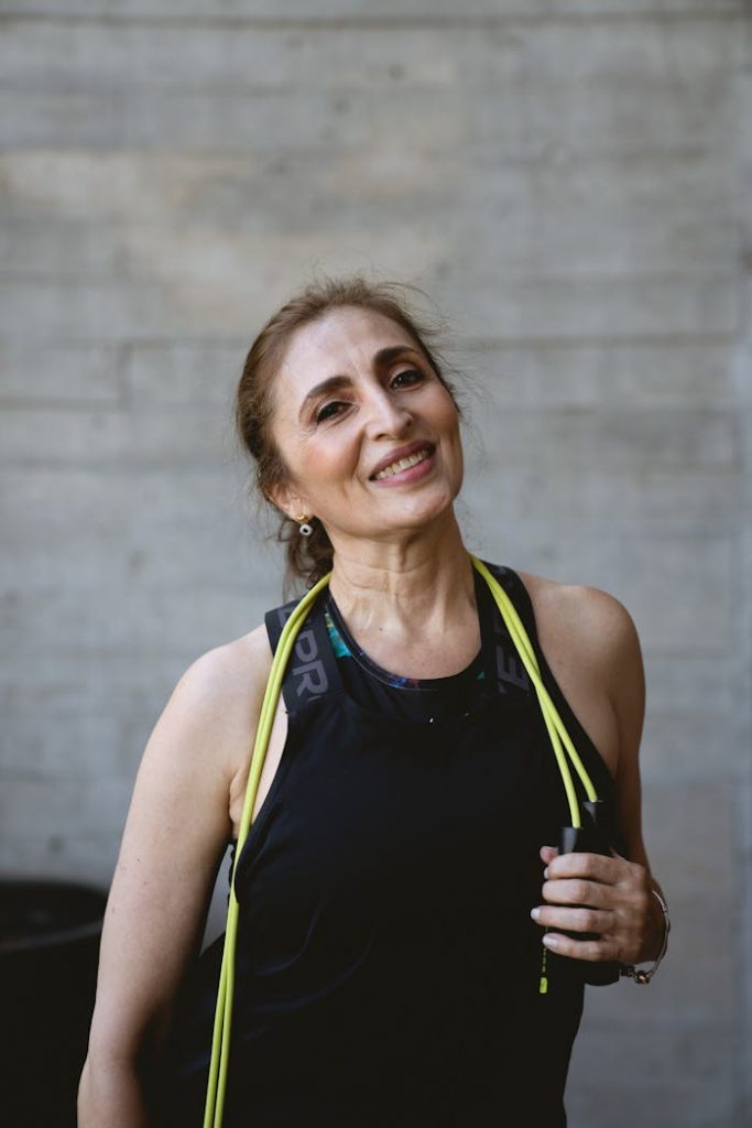 A joyful senior woman holding a jump rope while wearing sportswear, promoting active and positive aging.