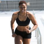 Fit woman with short hair jogging outdoors, showing strength and happiness.